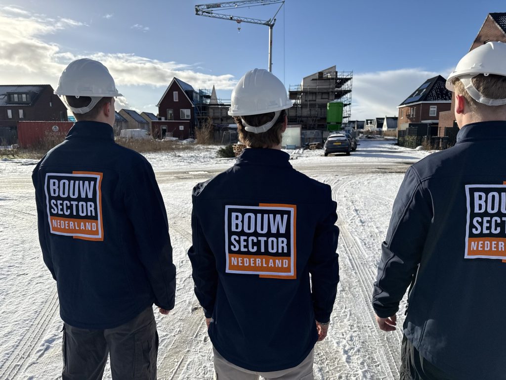 Drie vakmensen van Bouwsector Nederland met witte helm bij woningen in aanbouw